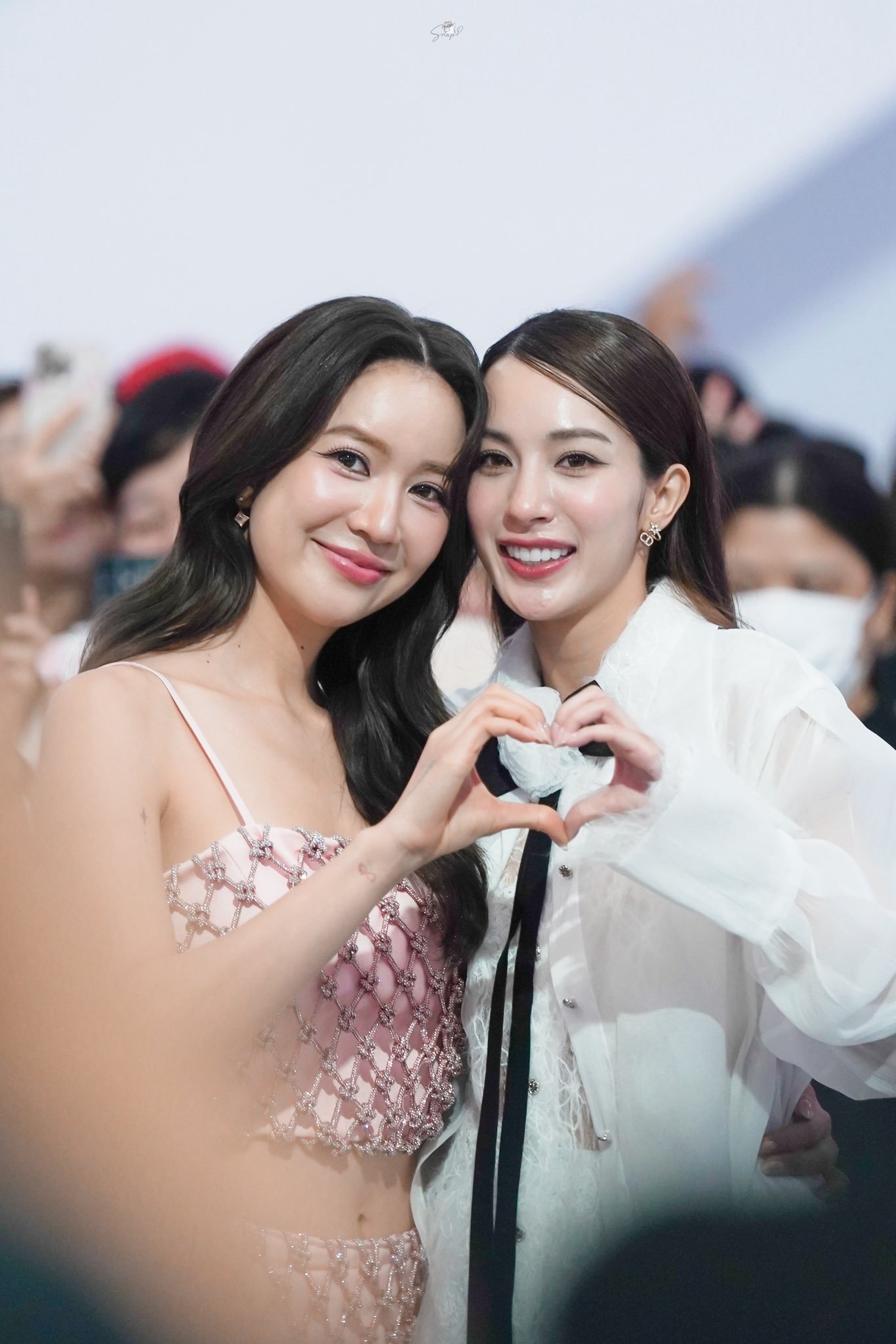Dupla GL EnjoyJune posa sorrindo e formando um coração com as mãos durante evento