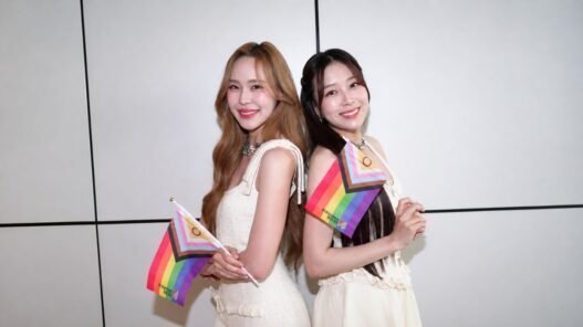 June e Mewnich, protagonistas de Whale Store xoxo, posam juntas segurando bandeiras do orgulho LGBTQIA+