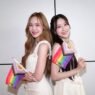 June e Mewnich, protagonistas de Whale Store xoxo, posam juntas segurando bandeiras do orgulho LGBTQIA+